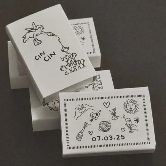 Cajas de cerillas de boda ilustradas con el dibujo de un brindis cin cin y la fecha