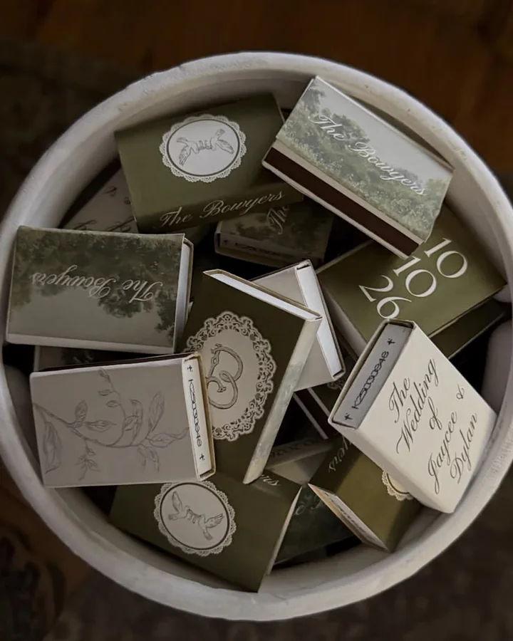 Cajas de cerillas de boda ilustradas en verde oliva y blanco, en un cuenco