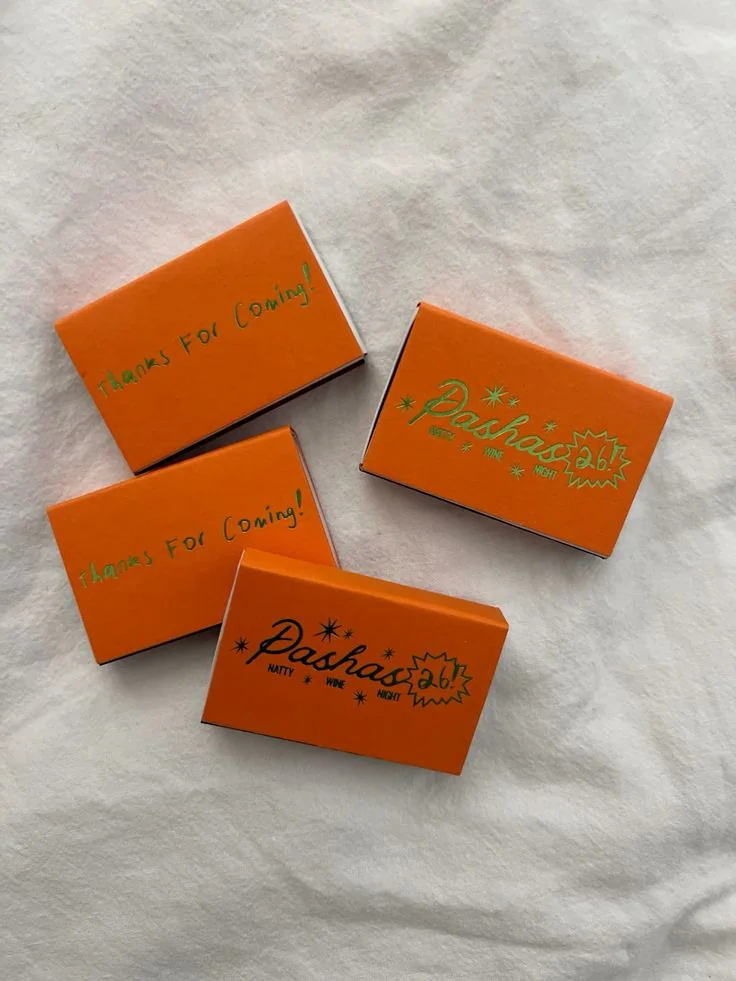 Orange matchboxes printed for a wine night, on a linen cloth