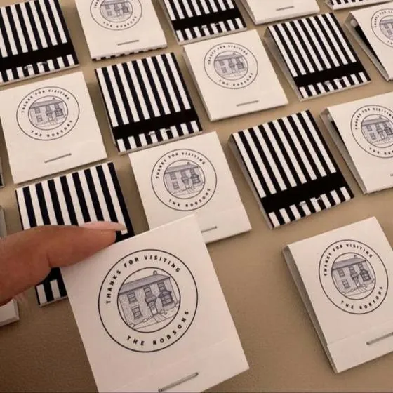 White matchbooks with a drawn house and Thanks for visiting, beside black and white striped covers